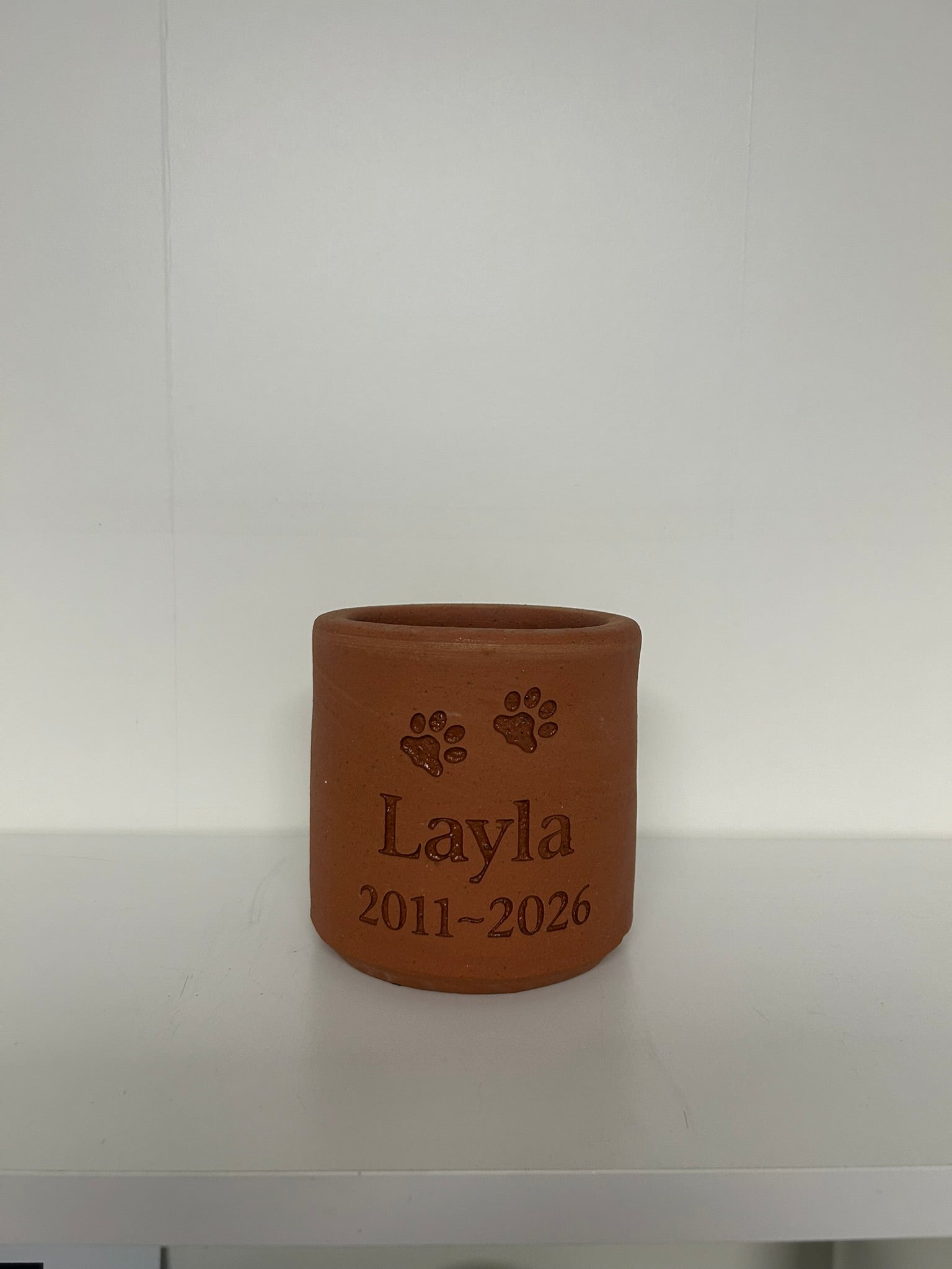 Brown ceramic planter with 'Layla' and paw prints engraved on a white background
