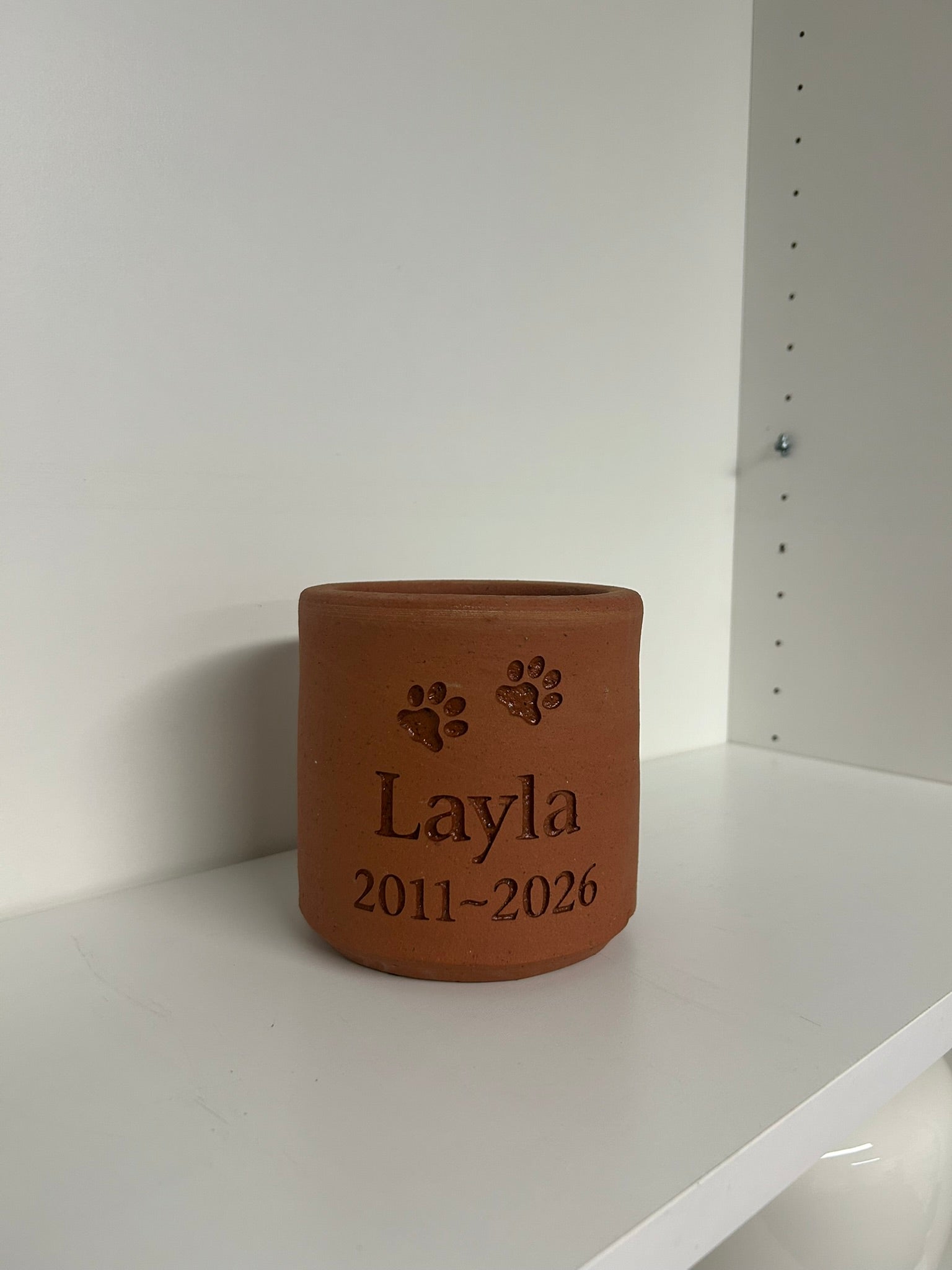 Terracotta pot with engraved text on a white surface