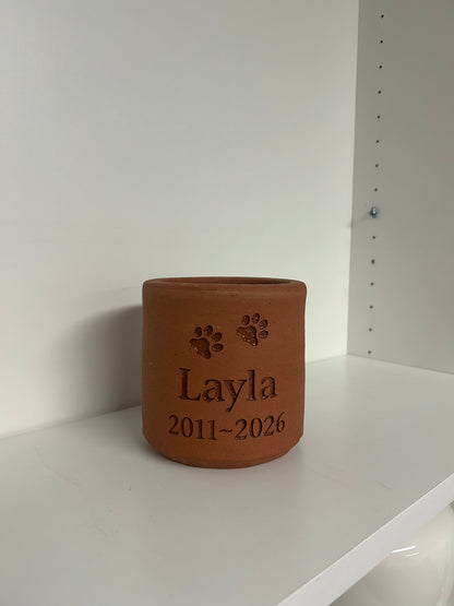 Terracotta pot with engraved text on a white surface